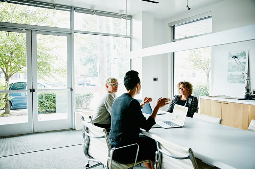 people in office around table talking