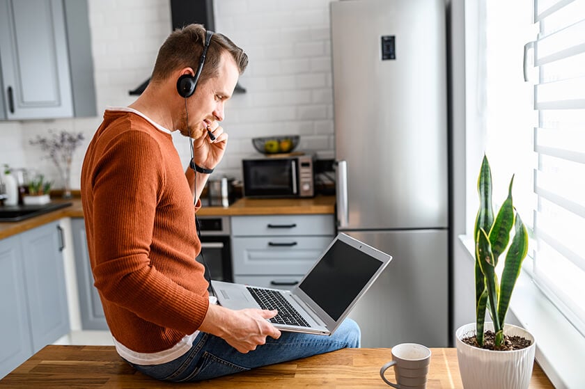 man holding laptop in kitchen with headset remote working man holding laptop in kitchen with headset remote working