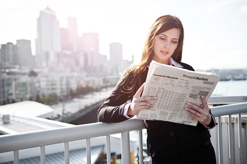 144562304 Woman leaning on fence reading newspaper